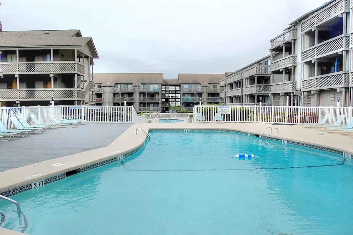 A wide view of Shipwatch Pointe’s outdoor swimming pool surrounded by lounge chairs and the condo buildings. The sparkling water, sunlit deck, and relaxed poolside atmosphere make the area inviting for sunbathing and unwinding after a day at the beach.