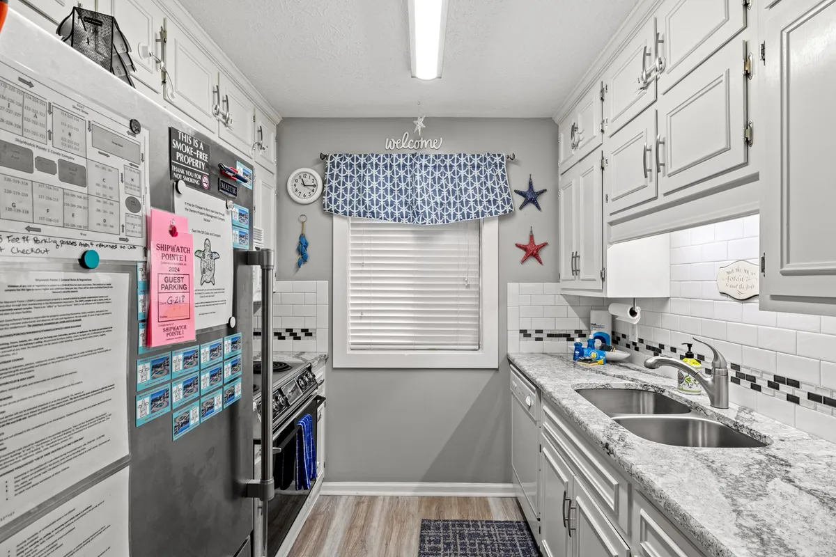 A modern kitchen scene with a stainless steel fridge adorned with colorful notes, expansive granite countertop, and bright blue and white curtains. Decorative stars echo those in the previous image, reinforcing a cohesive style. The space feels lively and well-equipped for both everyday meals and special celebrations.